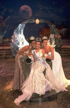 three women posing for a photo in front of an ice sculpture with the moon behind them