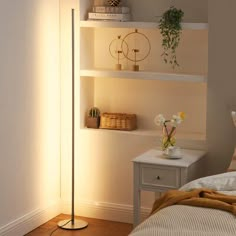 a bed room with a neatly made bed and a floor lamp next to the bed