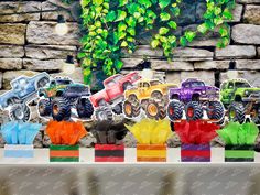 monster trucks are lined up in front of a stone wall