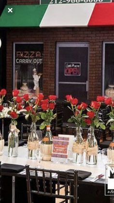 the tables are set up with vases and flowers in front of the storefront