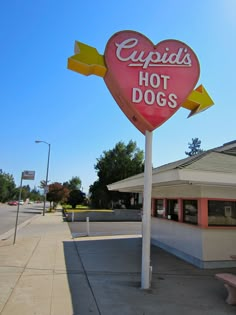 a heart shaped hot dog sign in front of a building