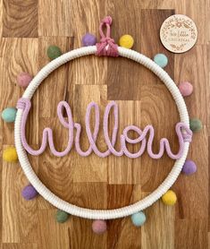 a white hoop with the word willow on it and pom - poms around it