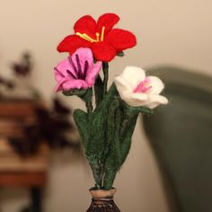 three flowers in a vase with green stems and red, white, and pink flowers