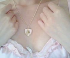 a woman wearing a necklace with a heart shaped pendant hanging from it's chest