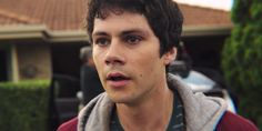 a young man is standing in front of a house with a surprised look on his face