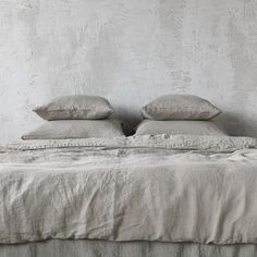 a bed with two pillows on top of it in front of a white painted wall