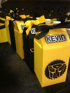 three yellow boxes with black and white designs on them, tied together by a ribbon