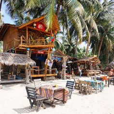 many tables and chairs are set up on the beach with palm trees in the background