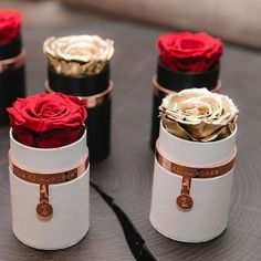 four small boxes with roses in them sitting on a table