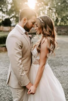 a bride and groom standing close together in front of the sun