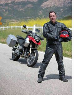 a man standing next to a motorcycle on the road