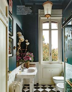 a bathroom with black and white checkered flooring next to a toilet, sink and window