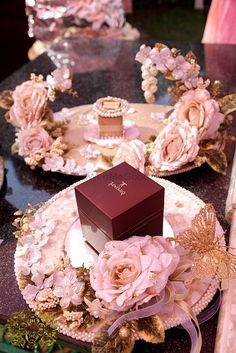 a table topped with plates covered in pink flowers and boxes filled with chocolates on top of them