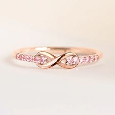 a rose gold ring with pink sapphires in the center and an intertwined band