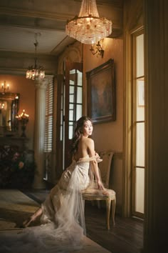 a woman sitting on top of a chair next to a chandelier in a room