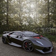 a black and red sports car parked on the side of a road next to trees