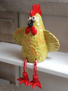 a ceramic chicken sitting on top of a window sill next to two red candles