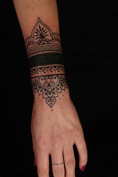 a woman's hand with a tattoo on it and a black band around the wrist