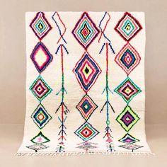 a multicolored rug with fringes and diamonds on the front, hanging from a wall