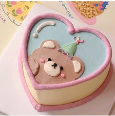 a cake shaped like a heart with a teddy bear in it's center, on top of a card