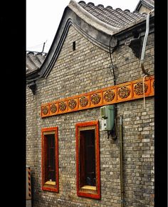 an old brick building with two windows and orange trim