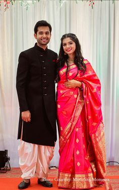 a man and woman standing next to each other in front of a white wall with curtains