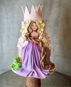 a figurine is sitting on top of a wooden stand with a purple dress and crown