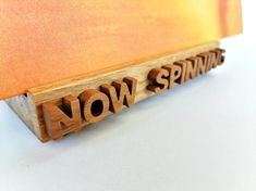 the word now spelled with wooden letters on a white surface