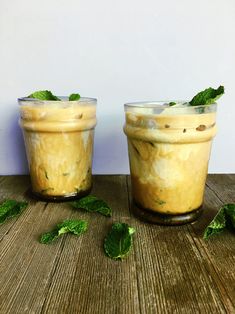 two glasses filled with dessert sitting on top of a wooden table next to each other