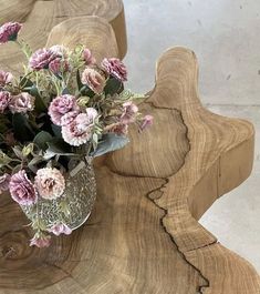 a vase filled with pink flowers sitting on top of a wooden table next to two chairs