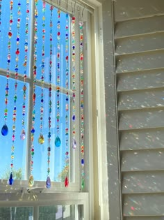 a window with beads hanging from it's side and the sky in the background