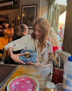 a woman is holding a small item in her hand at a table with other people