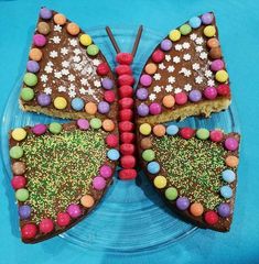 a butterfly shaped cake on a blue plate with sprinkles and candies