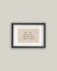 a black and white frame with a handwritten quote on it, against a gray wall