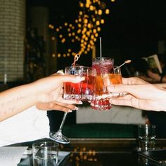 several people are toasting with drinks in their hands at a party or social gathering