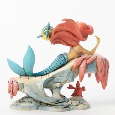 a figurine of a mermaid sitting on top of a fish