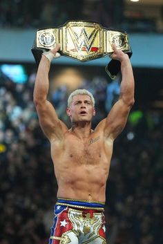 a man holding up a wrestling belt in the air