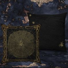 two black and gold decorative pillows against a dark blue wall with spider webs on it