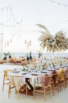 an outdoor dining area with tables and chairs set up for a wedding reception at the beach