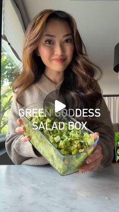 a woman is holding a salad box in her hands