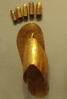 an ancient gold object is on display in a museum setting with several smaller brass objects around it