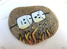 two marshmallows sitting on top of a rock with flames painted on it