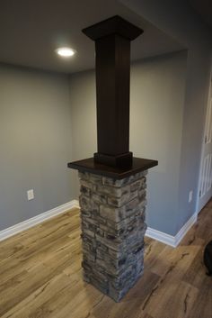 an empty room with a stone fireplace and hard wood flooring on the hardwood floors