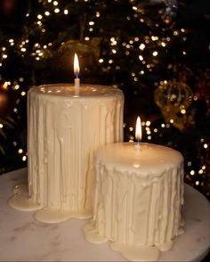 two white candles sitting on top of a table