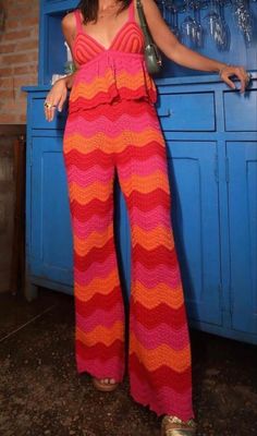 a woman standing in front of a blue cabinet wearing a pink and orange striped jumpsuit