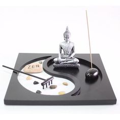 a small buddha statue sitting on top of a yin - yang clock with two balls