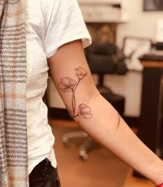 a woman's arm with a flower tattoo on the left side of her arm