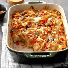 a green casserole dish filled with pasta and vegetables