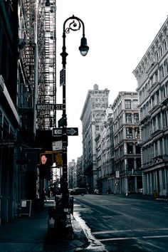 an empty city street with tall buildings on both sides and a traffic light in the middle