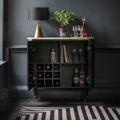 a black and white striped rug in front of a shelf with bottles, glasses and a potted plant